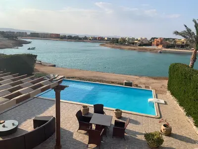 a swimming pool next to a body of water at 3Bedrooms Villa with Private Pool and direct Lagoon Access in Hurghada