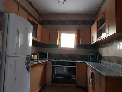 a kitchen with a white refrigerator and wooden cabinets at Jasmine villa in Hurghada