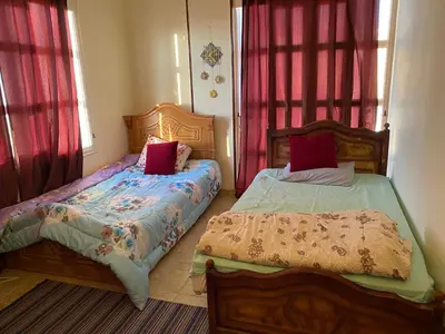two beds in a bedroom with red curtains at PORTO HILL in Hurghada