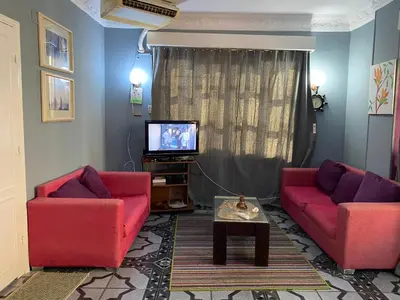 a living room with two red couches and a tv at PORTO HILL in Hurghada