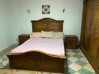 a bedroom with a wooden bed and two night stands at PORTO HILL in Hurghada