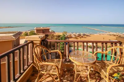 a balcony with chairs and tables and a beach at All View Apartements Hurghada in Hurghada