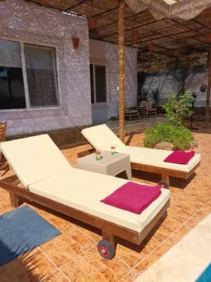 two beds and a table on a patio at Rum i villa med pool in Hurghada