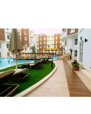 a swimming pool with chairs and an umbrella in a building at Aqua Palms resort -Lovely studio in Hurghada