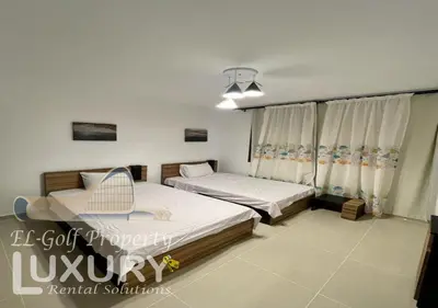 a bedroom with two beds and a chair in it at G-Cribs 2 Bed Rooms in Hurghada
