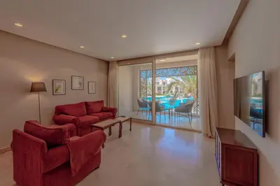 a living room with two red chairs and a tv at Elegant 2-Bedroom Apartment in Mangroovy, Pool & Beach in Hurghada