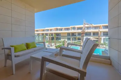 a balcony with a couch and chairs and a view of a building at Boho-Chic Studio Apartment in G-Cribs, Pool View in Hurghada