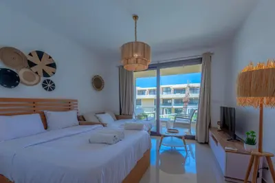 a bedroom with two beds and a large window at Boho-Chic Studio Apartment in G-Cribs, Pool View in Hurghada