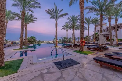 a pool with palm trees in a resort at Classy 1-Bedroom Apartment in Ancient Sands with Pool View in Hurghada