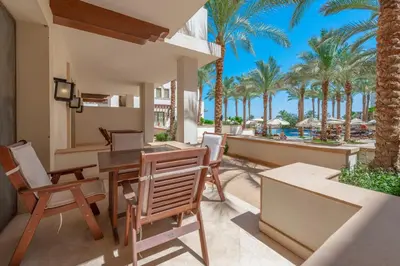 an outdoor patio with a table and chairs and palm trees at Classy 1-Bedroom Apartment in Ancient Sands with Pool View in Hurghada