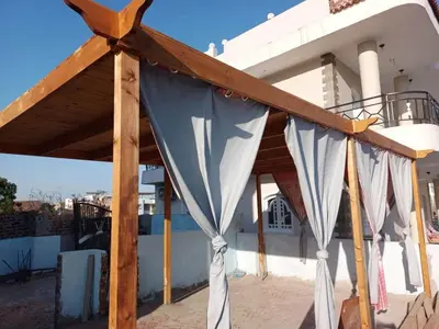 a wooden canopy in front of a house at Villa Victoria Old Nile View in Luxor