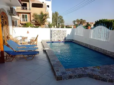 a swimming pool with two chairs and a table at Villa Victoria Old Nile View in Luxor