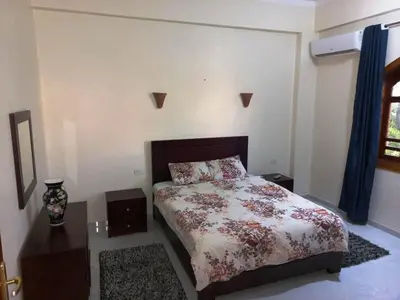a bedroom with a bed with a floral bedspread and a table at Villa Victoria Old Nile View in Luxor