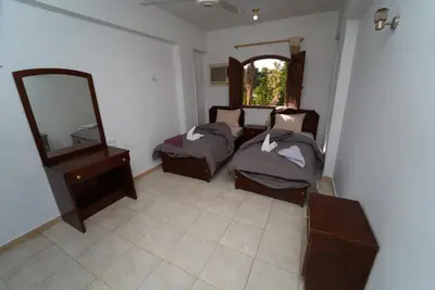 a room with two beds and a mirror and a dresser at Flower of Desert in Luxor