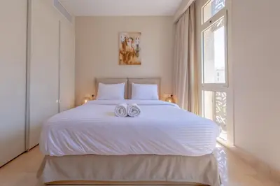 a bedroom with a white bed with two towels on it at High Standard 2-Bedroom in Mangroovy Residence, Pool View & Beach in Hurghada