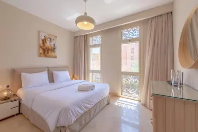 a bedroom with a large bed and two windows at High Standard 2-Bedroom in Mangroovy Residence, Pool View & Beach in Hurghada