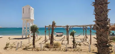 a beach with a lighthouse and a hammock on the beach at Soma Bay Ambiance - Relaxed Apartment - Next to The Breakers in Hurghada