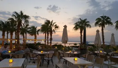 a restaurant with tables and umbrellas and palm trees at Soma Bay Ambiance - Relaxed Apartment - Next to The Breakers in Hurghada