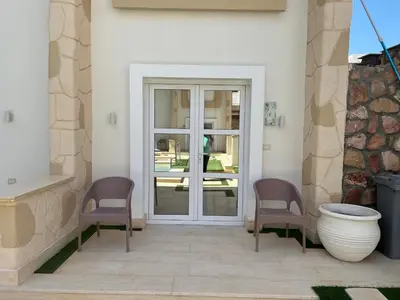 a patio with two chairs and a white door at Boka Bay One in Hurghada