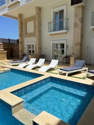 a villa with a swimming pool and lounge chairs at Boka Bay One in Hurghada