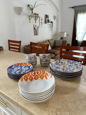 a table with plates and bowls on top of it at Sabina 1br apartment Lagoon view with shared pool By BFG Beit Fel Gouna in Hurghada