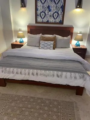 a bedroom with a large bed with two night stands at Sabina 1br apartment Lagoon view with shared pool By BFG Beit Fel Gouna in Hurghada