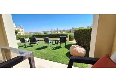 a patio with chairs and a table on the grass at El Gouna Waterside, 2-Bd Ground Floor Sleeps 4 Persons in El Gouna