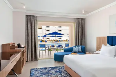 a hotel room with a bed and a view of a pool at Pickalbatros Blu Spa Resort - Adults Friendly 16 Years Plus- Ultra All-Inclusive in Hurghada
