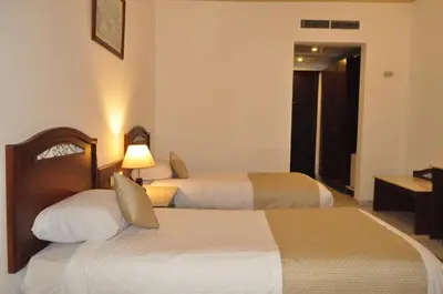 a hotel room with two beds and a television at Dexon Roma Hotel in Hurghada