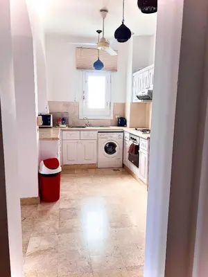 a kitchen with white cabinets and a red trash can at South Marina Apartment Wi-Fi available in Hurghada