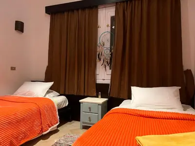 a bedroom with two beds with orange sheets and a window at South Marina Apartment Wi-Fi available in Hurghada