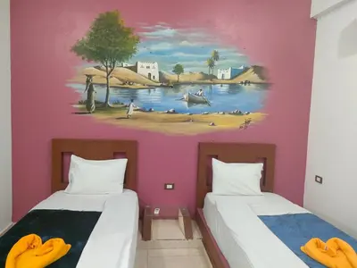 two beds in a room with a painting on the wall at Nukud guest house in Aswan