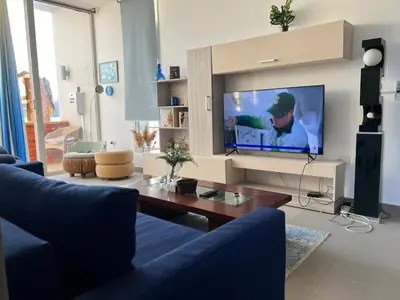 a living room with a blue couch and a flat screen tv at Lovely 1 Bedroom with private heated Jacuzzi at Sholan El Gouna in Hurghada