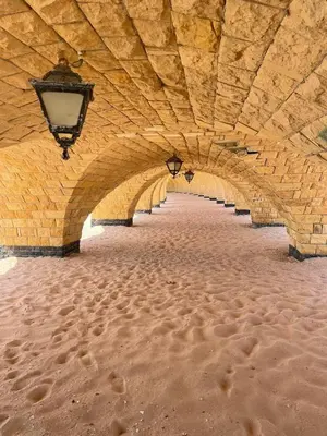 a stone tunnel with a street light and footprints in the sand at Apartman Andalusie in Hurghada