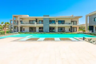 a villa with a swimming pool in front of a building at Cozy 2-Bedroom Apartment in G-Cribs, El Gouna. Terrace & Pool in Hurghada