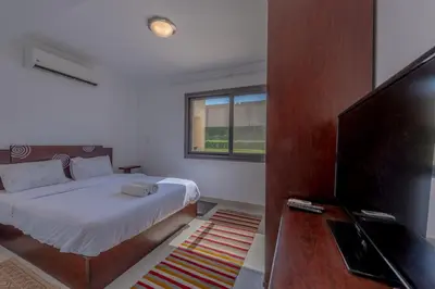 a bedroom with a bed and a flat screen tv at Cozy 2-Bedroom Apartment in G-Cribs, El Gouna. Terrace & Pool in Hurghada