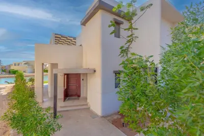 a white house with a door in a yard at Light-Filled 4-Bedroom Villa in Tawila, El Gouna. Jacuzzi & Lagoon in Hurghada