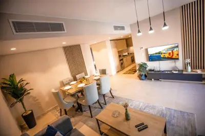 a living room with a tv and a table and chairs at Luxurious Sea view 2 BR & private Garden to the pool at Mangroovy in Hurghada