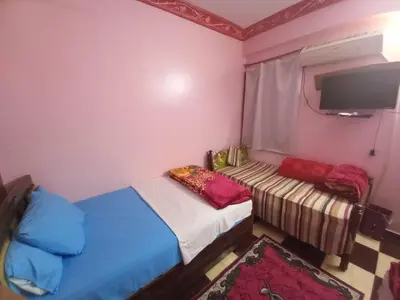 a small room with two beds and a tv at Sabrina home in Aswan