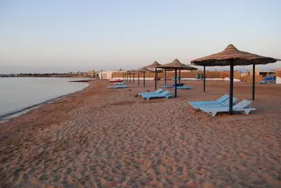 a beach with umbrellas and chairs on the sand at Cecelia resort in Hurghada