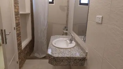 a bathroom with a sink on a counter with a shower at Family House in Luxor