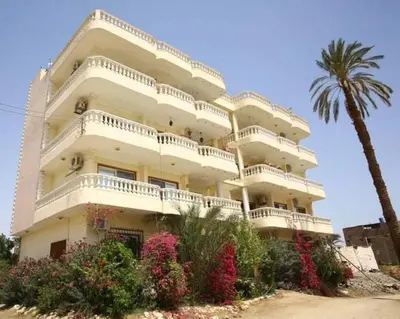 a large white building with a palm tree and flowers at Egypt sun accommodation Spiritualities in Luxor