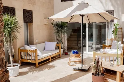 a patio with a couch and an umbrella at Nayah Stays, Amazing villa with private pool & 5 master suites in Hurghada