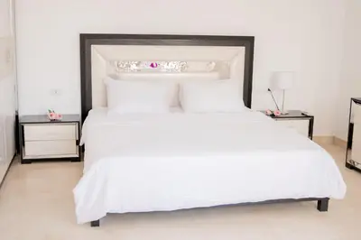 a large white bed with white sheets and pillows at Nayah Stays, Amazing villa with private pool & 5 master suites in Hurghada