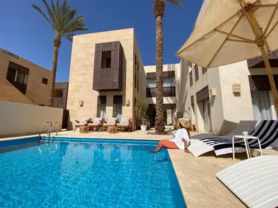 a woman sitting on a chair next to a swimming pool at Nayah Stays, Amazing villa with private pool & 5 master suites in Hurghada