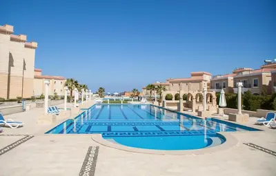 a pool at a resort with chairs and trees at selena bay in Hurghada