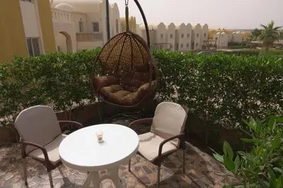 a patio with a table and chairs and a swing at Private 1 bedroom flat with garden in Makadi in Hurghada