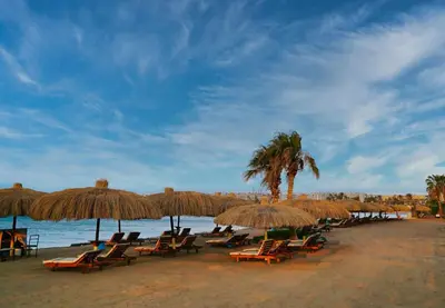 a group of chairs and umbrellas on a beach at New Eagles Downtown Zahabia Resort & Aqua Park in Hurghada