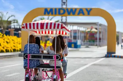 two girls sitting in a stroller under an umbrella at a playground at Neverland City Hurghada - Pickalbatros in Hurghada