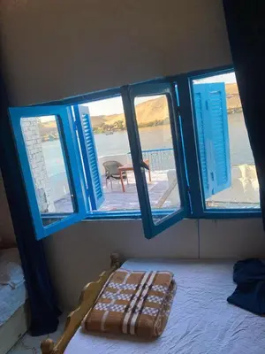 a room with blue windows and a bed with a table at hooly nubian in Aswan